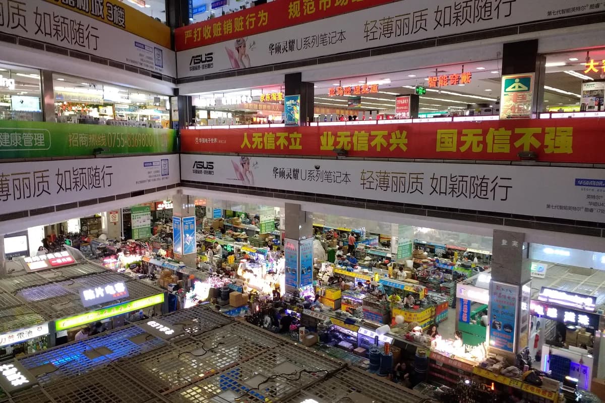Inside Huaqiang Electronic World with stacked electronics stalls and Chinese shop signs