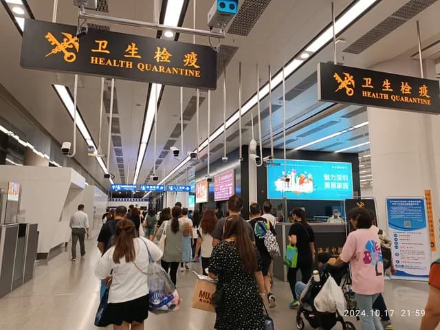 Travelers walking through Futian Port health quarantine and border signage