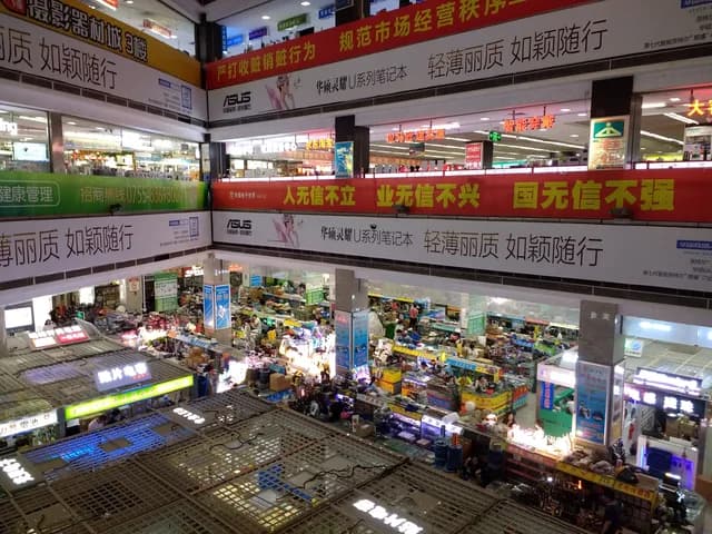 Inside Huaqiang Electronic World with stacked electronics stalls and Chinese shop signs