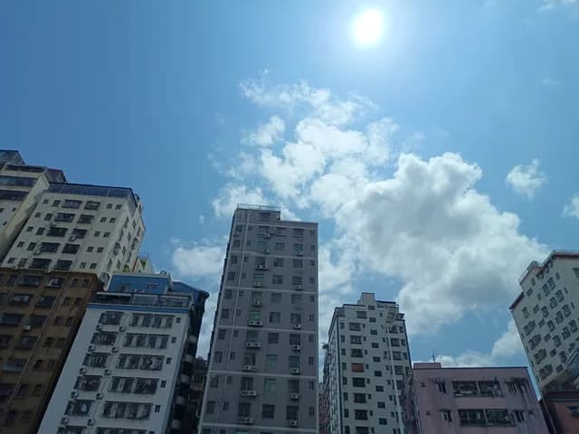 Looking up at Shenzhen apartment towers and bright sky from street level