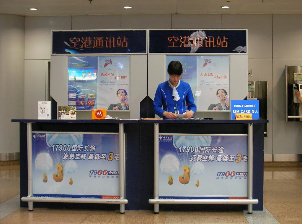 China Mobile SIM card counter in the arrivals hall at Beijing Capital Airport, with a China Mobile SIM card sign on the desk