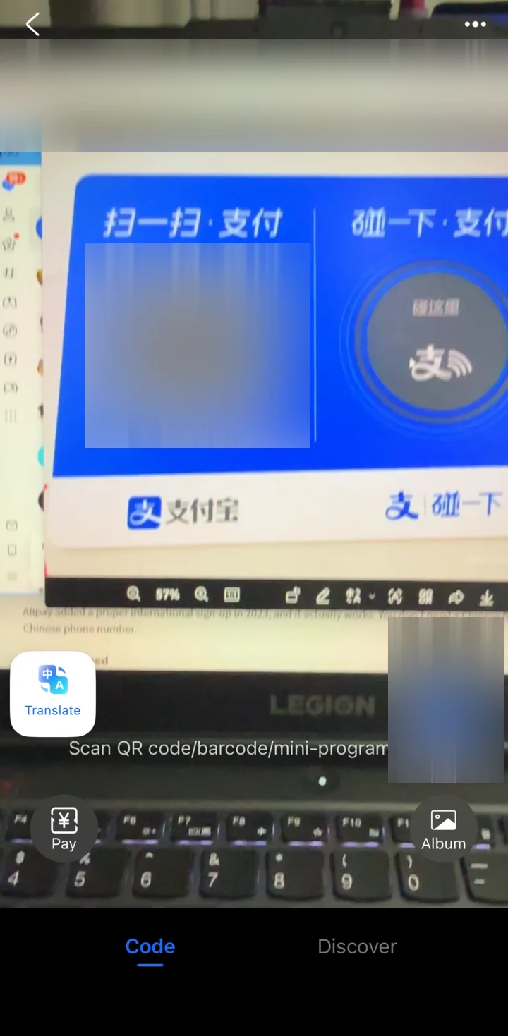 Alipay Scan camera pointed at a QR code stand on a laptop screen during a test