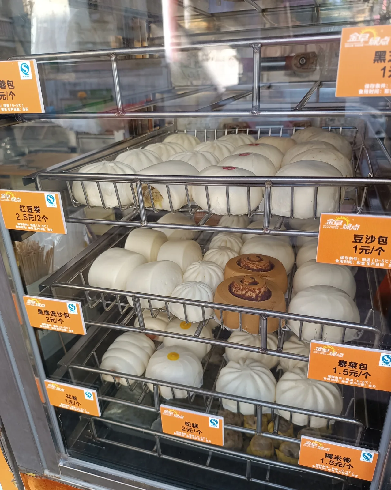 Glass steamer case of baozi and buns with price tags, such as 1.5 yuan for a vegetable bun