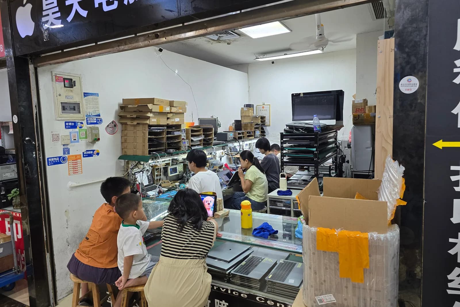 深圳・華強電子世界の中で、作業台に向かってノートパソコンを修理する技術者たち