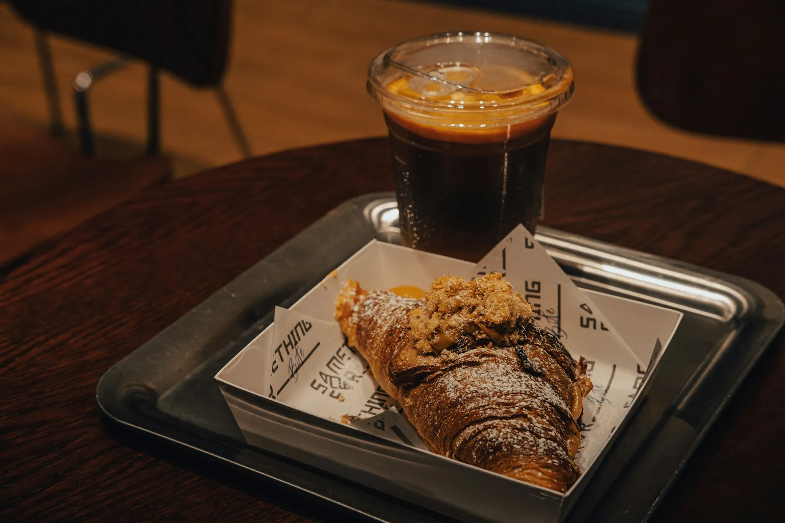 カフェの金属トレーにのったアイスアメリカーノとクロワッサン