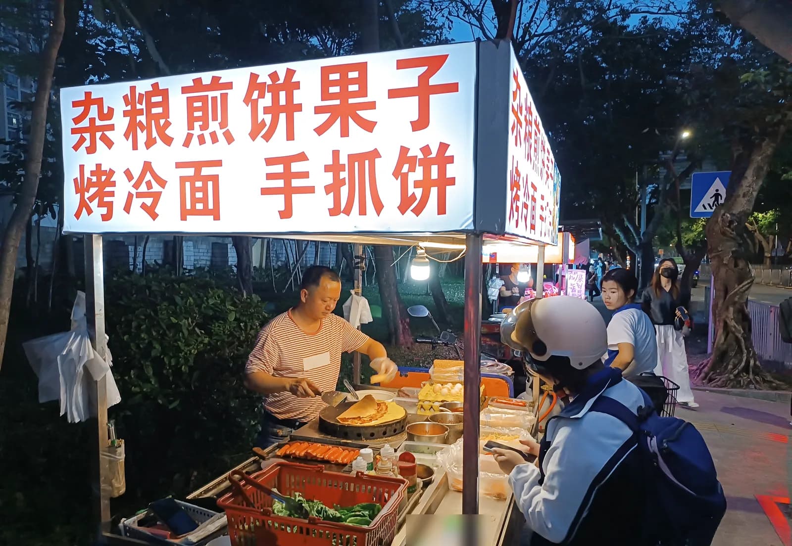 Jianbing street stall in Nanshan, Shenzhen, with a crepe cooking on the round griddle