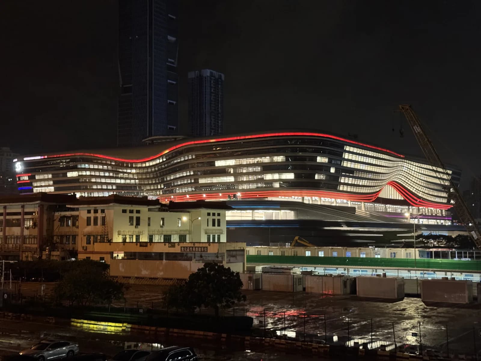 New Huanggang Port building lit up before dawn in August 2026, with construction cranes still beside it