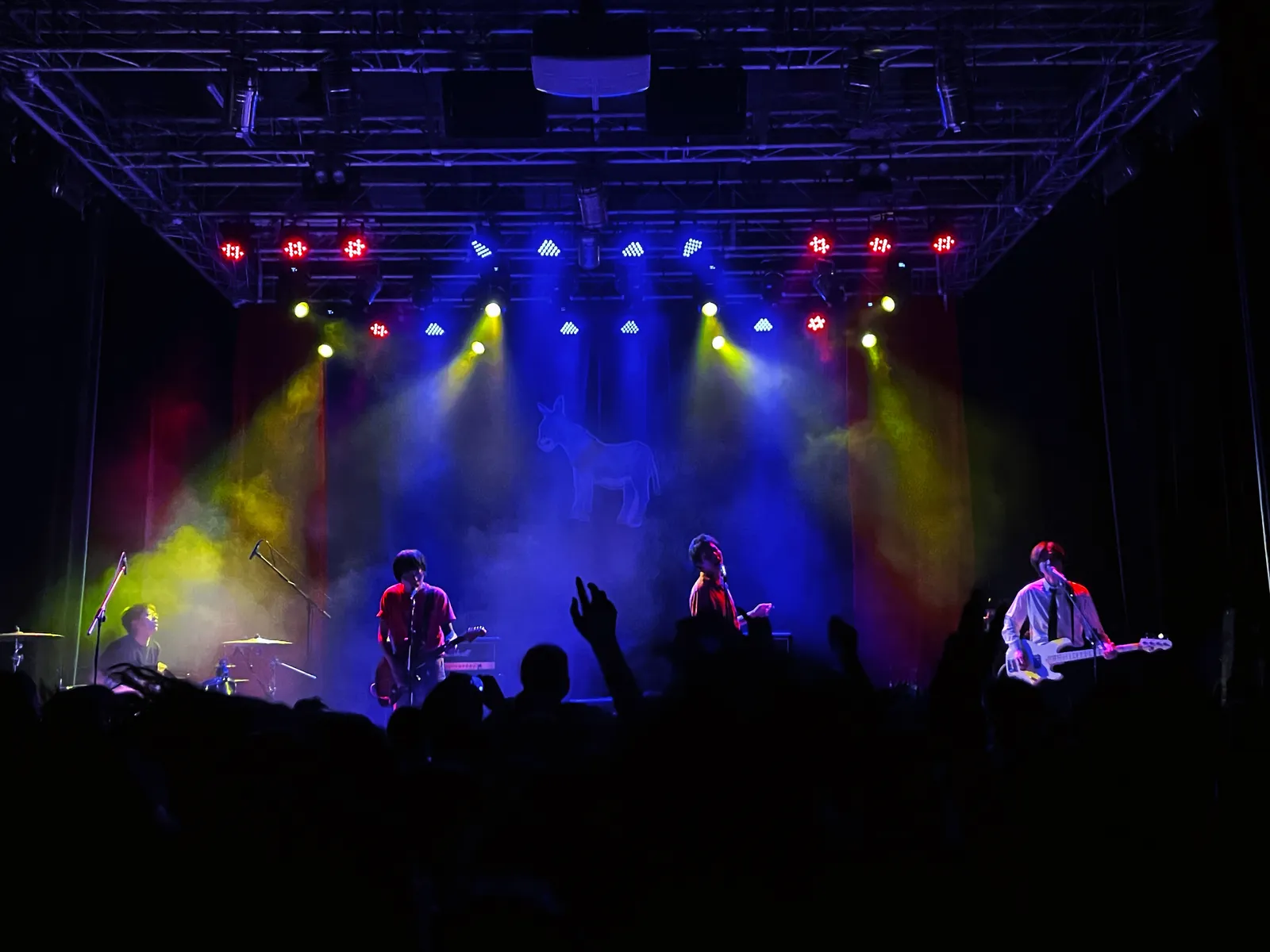 Band playing under coloured stage lights at B10 Live in OCT-LOFT, with the crowd in silhouette