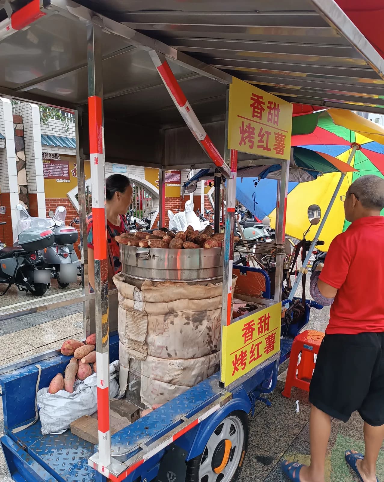 Roasted sweet potato cart in Longhua, Shenzhen, with sweet potatoes piled on a barrel oven