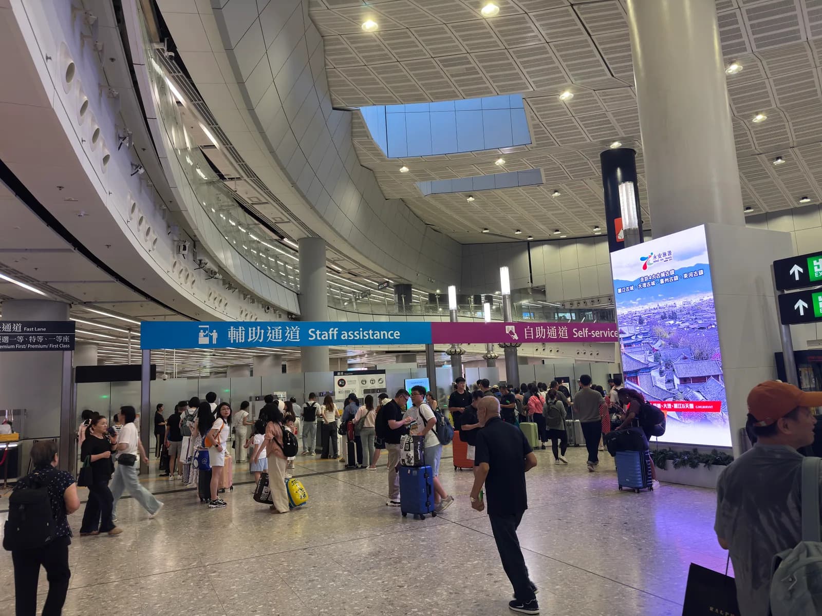 Hong Kong West Kowloon Station departure hall with staff assistance and self-service signs, August 2026