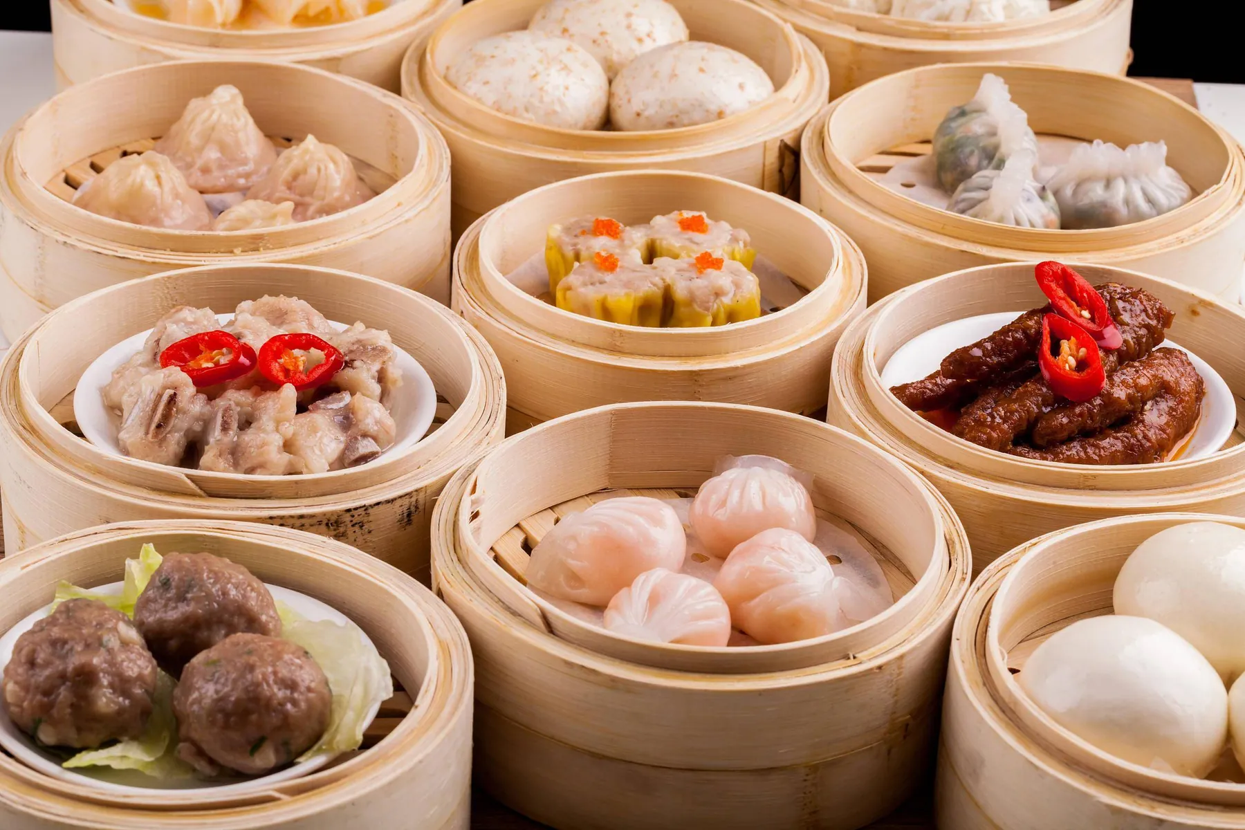 Open bamboo steamers of har gow, siu mai, spare ribs and buns seen from above