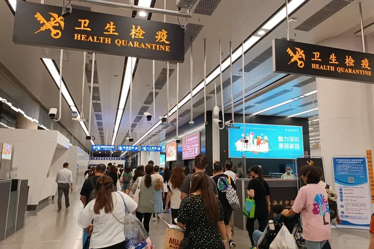 Travelers walking through Futian Port health quarantine and border signage