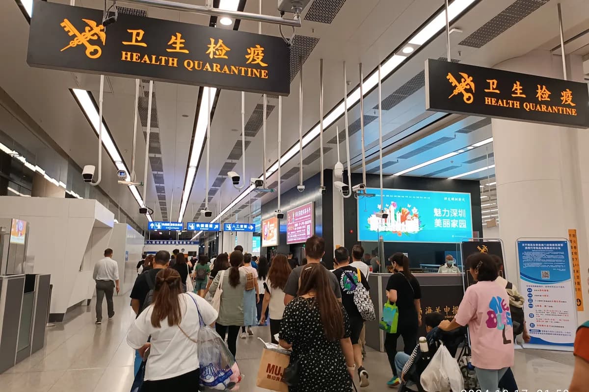 Travelers walking through Futian Port border signage in Shenzhen