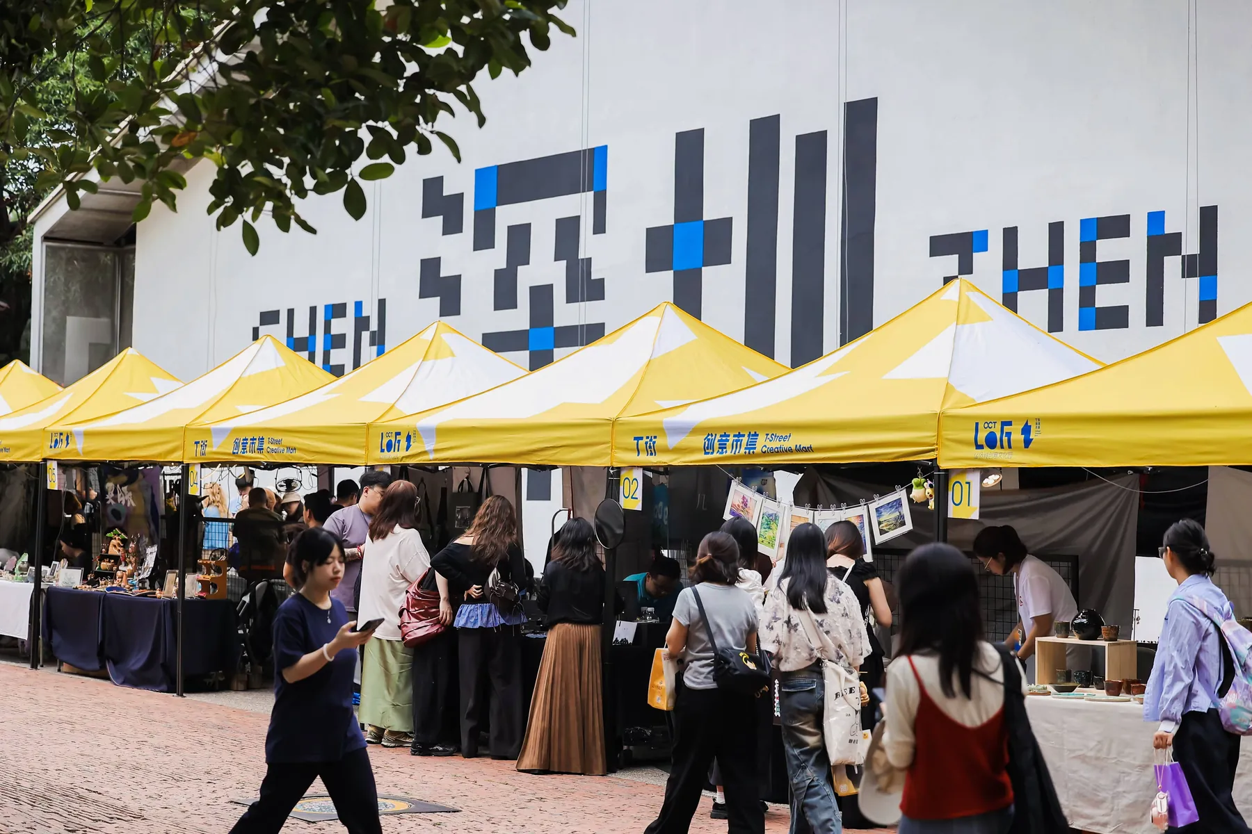 Crowds at T-Street Creative Market stalls in front of the Shenzhen lettering wall at OCT-LOFT