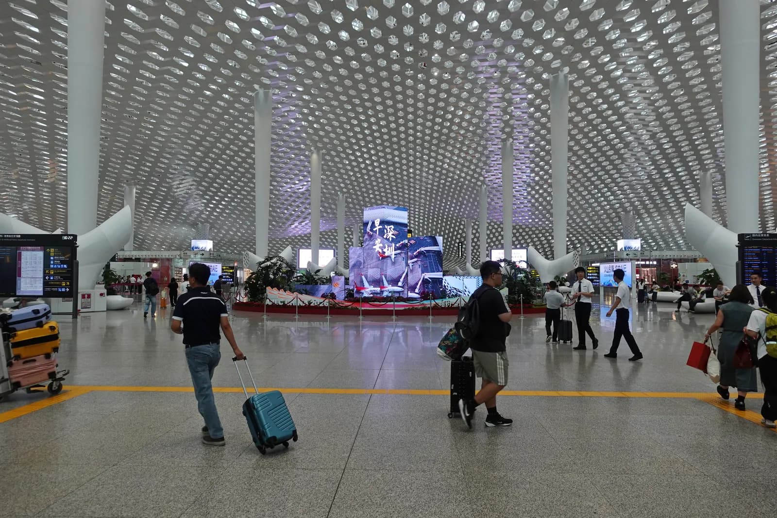Travellers with suitcases crossing the Terminal 3 hall at Shenzhen Bao'an International Airport