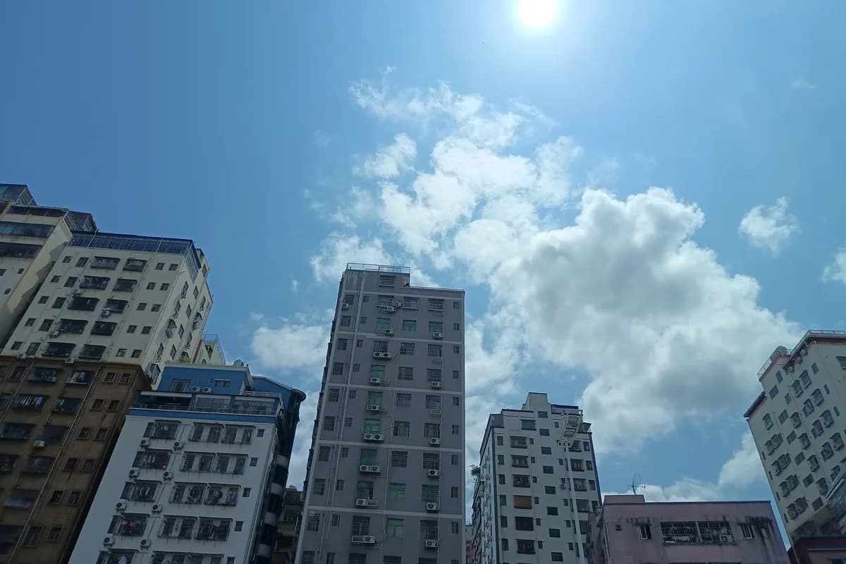 Looking up at Shenzhen apartment towers and bright sky from street level