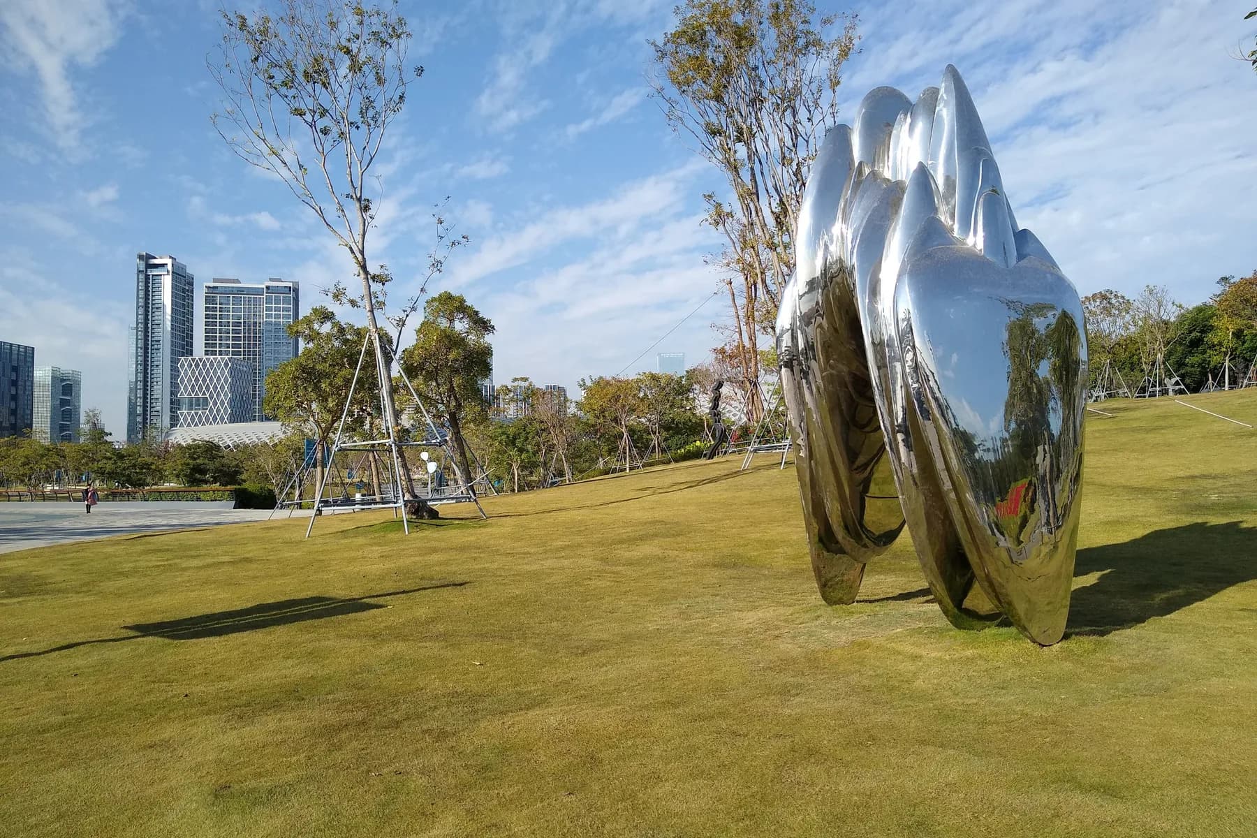 Sunny green lawn and sculpture under clear autumn skies at Shenzhen Bay Park in Nanshan