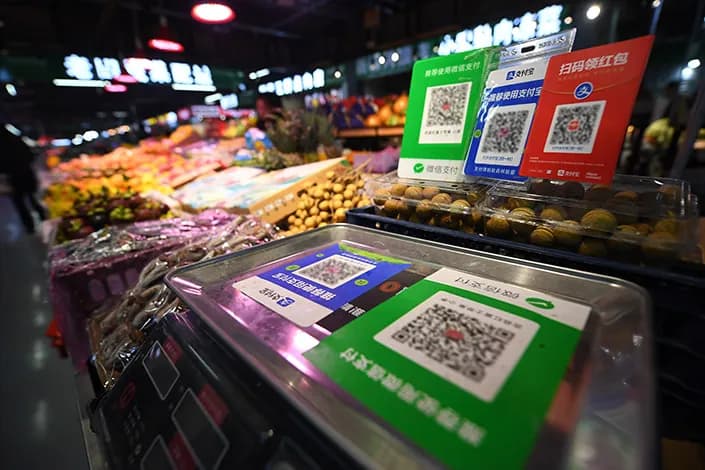 Alipay and WeChat Pay QR code signs on a fruit market stall in Shenzhen