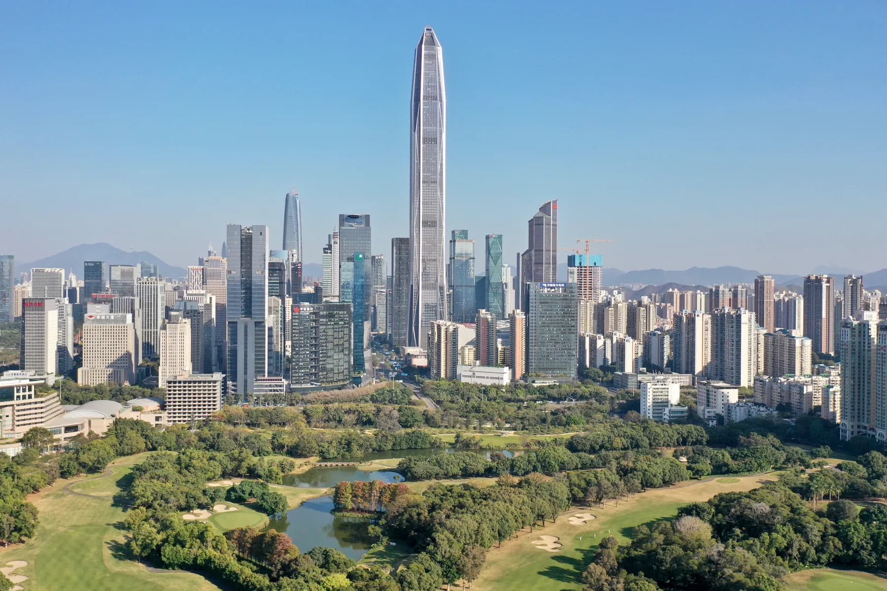 Aerial view of Futian CBD and Ping An Finance Centre above a green golf course